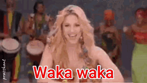 a woman is smiling in front of a group of drummers and the words waka waka are on the screen
