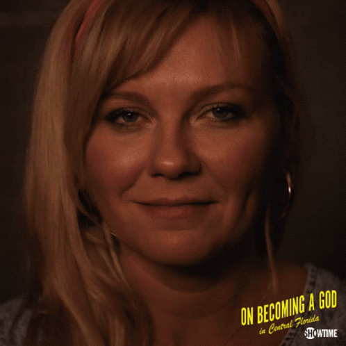 A Woman Is Smiling In Front Of A Poster That Says On Becoming A God In Central Florida GIF