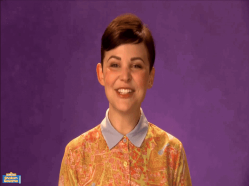 A Woman Is Smiling In Front Of A Purple Background That Says Shabbat Shalom On It GIF