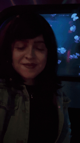 A Woman Is Smiling In Front Of A Screen That Says Shagarita On It GIF