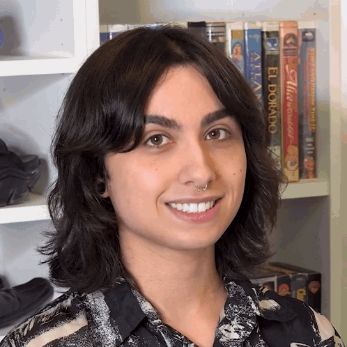 A Woman Is Smiling In Front Of A Shelf With Books Including El Dorado GIF