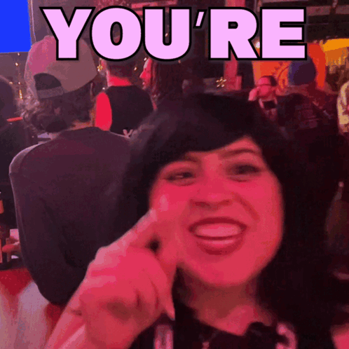 A Woman Is Smiling In Front Of A Sign That Reads You 'Re GIF