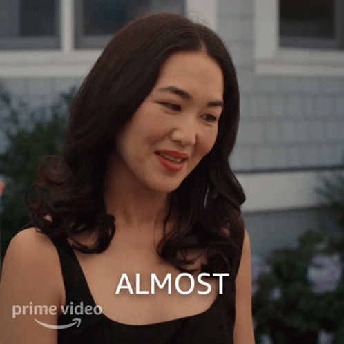 A Woman Is Smiling In Front Of A Sign That Says Almost On It GIF