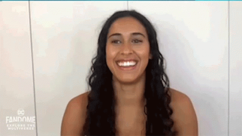 a woman is smiling in front of a white wall .
