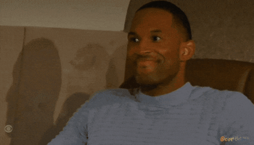 A Woman Is Smiling In Front Of A Window With Blinds And The Word Cor-Icon On The Bottom GIF