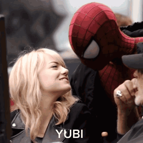 A Woman Is Smiling Next To A Man In A Spiderman Costume With The Word Yubi On The Bottom Right GIF