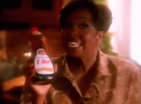 a woman is smiling while holding a bottle of ketchup .