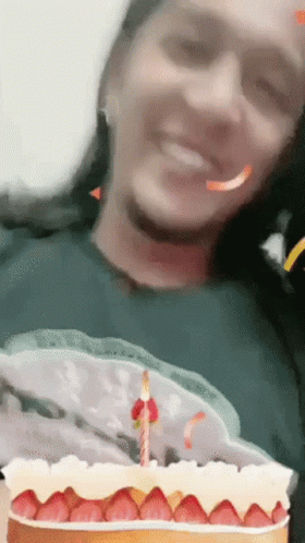 A Woman Is Smiling While Holding A Cake With Strawberries On It GIF