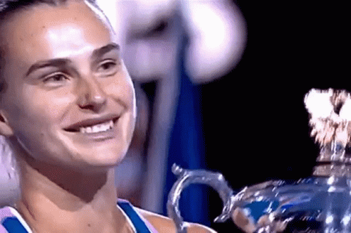 a woman is smiling while holding a trophy in her hands .