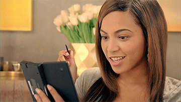 a woman is smiling while looking at a tablet with a pen in her hand