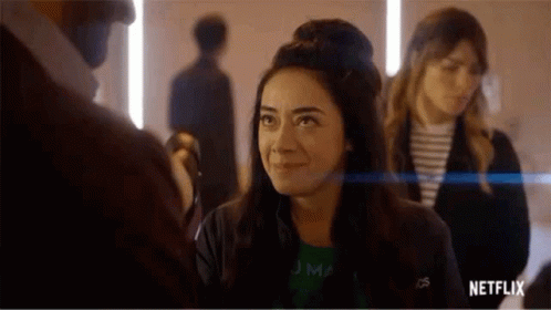 A Woman Is Smiling While Standing Next To A Man In A Room With Other People . GIF