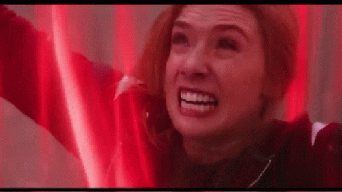 A Woman Is Smiling With Her Arms In The Air In A Red Light . GIF