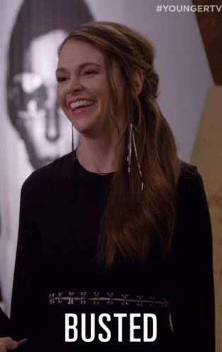 A Woman Is Smiling With The Word Busted Written On Her Chest GIF