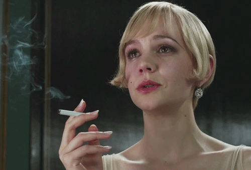A Woman Is Smoking A Cigarette In Front Of A Window GIF