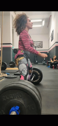 A Woman Is Squatting With A Barbell That Says Leiko GIF