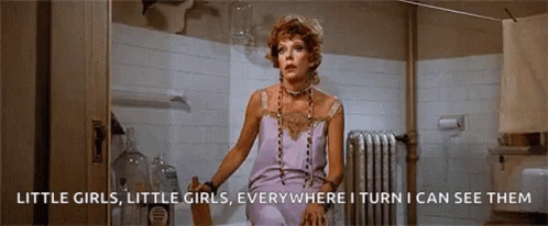 A Woman Is Standing In A Bathroom With The Words Little Girls Little Girls Everywhere I Turn I Can See Them On The Botto GIF