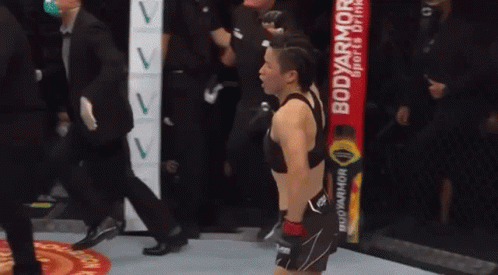 a woman is standing in a boxing ring with a body armor drink in the background .