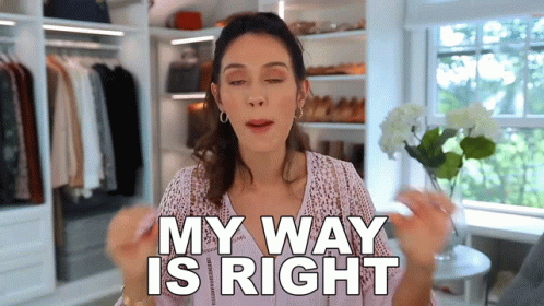 a woman is standing in a closet holding a flower and saying my way is right .