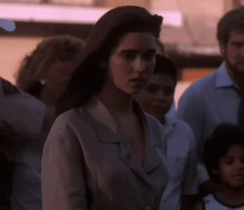 A Woman Is Standing In A Crowd Of People And Looking At The Camera GIF