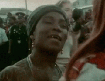 A Woman Is Standing In A Crowd Of People And Smiling . GIF
