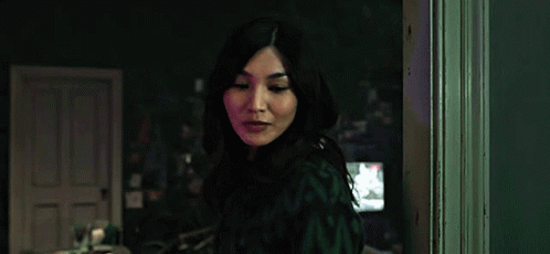 A Woman Is Standing In A Dark Room In Front Of A Door . GIF