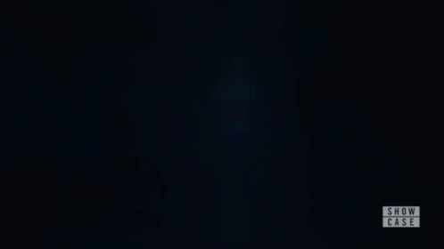 a woman is standing in a dark room with her eyes closed and a show case logo in the corner .