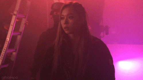 a woman is standing in a dark room with purple lights and the words gifsaespa on the bottom