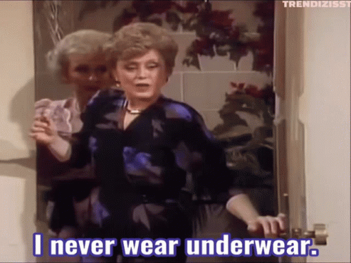 A Woman Is Standing In A Doorway Holding A Glass And Saying " I Never Wear Underwear " GIF
