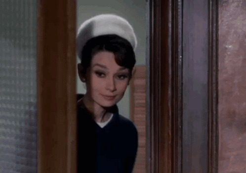 Woman Standing In Doorway Wearing Hat And Blue Shirt GIF