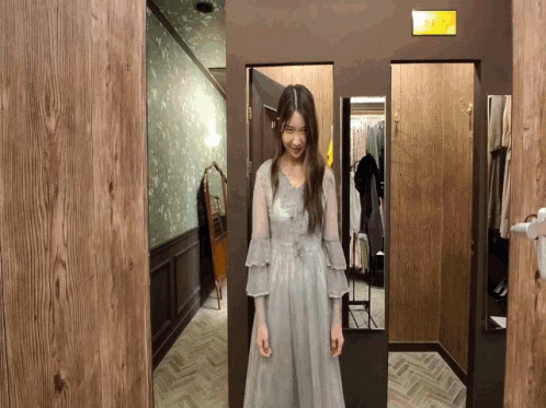 A Woman Is Standing In A Dressing Room With A Sign That Says Exit GIF