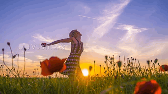 A Woman Is Standing In A Field With Her Arms Outstretched At Sunset GIF