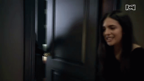 A Woman Is Standing In A Hallway With A Tv Screen Behind Her That Says Tci GIF