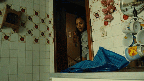 A Woman Is Standing In A Kitchen With A Blue Tarp On The Counter GIF