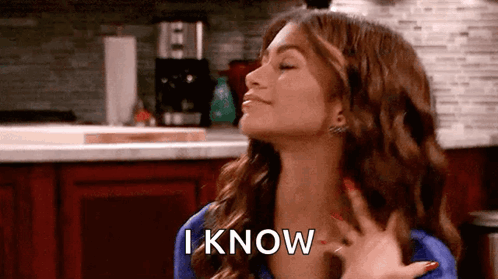 A Woman Is Standing In A Kitchen With Her Eyes Closed And Her Hand On Her Chest And The Words `` I Know '' . GIF
