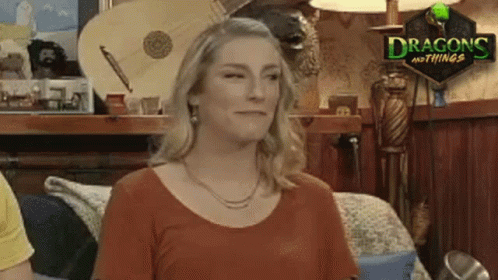 A Woman Is Standing In A Room With A Sign That Says Dragons And Things On It . GIF