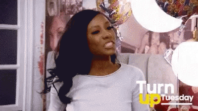 A Woman Is Standing In A Room With Balloons And A Sign That Says Turn Up Tuesday GIF
