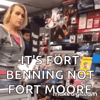A Woman Is Standing In A Store With The Words `` It 'S Fort Benning Not Fort Moore '' Written On Her Face . GIF