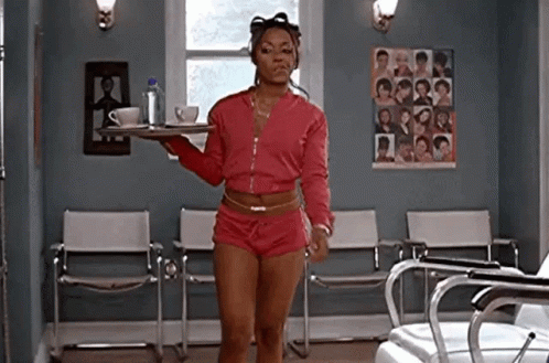 a woman is standing in a waiting room holding a tray of coffee and tea .
