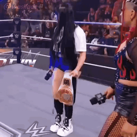 A Woman Is Standing In A Wrestling Ring Holding A Bag Of Food And A Microphone . GIF