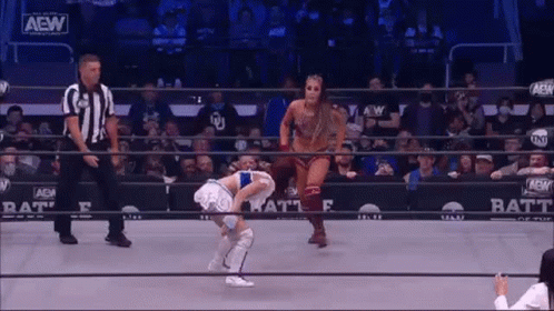 a woman is standing in a wrestling ring with a referee .