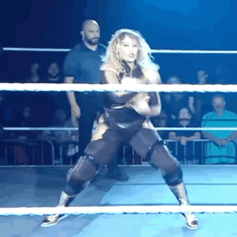 a woman is standing in a wrestling ring with a referee in the background