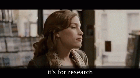 A Woman Is Standing In Front Of A Bookshelf In A Bookstore And Talking About Research . GIF