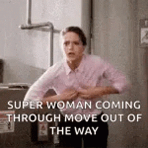 A Woman Is Standing In Front Of A Box And Holding Her Chest . GIF