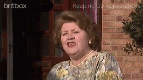 A Woman Is Standing In Front Of A Brick Wall With The Words Britbox Keeping Up Appearances Behind Her GIF