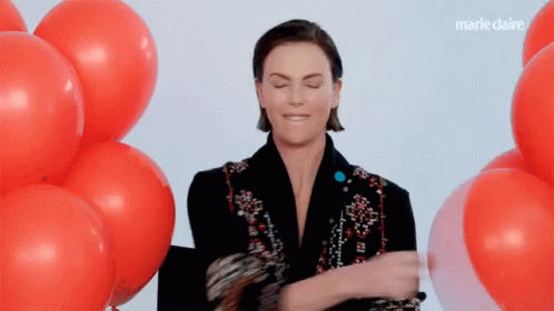 A Woman Is Standing In Front Of A Bunch Of Red Balloons With Marieclaire Written On The Bottom GIF
