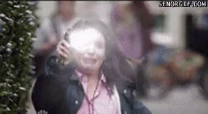 A Woman Is Standing In Front Of A Bush With Her Eyes Closed And A Blurred Background . GIF