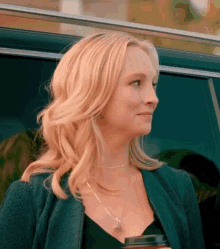 A Woman Is Standing In Front Of A Car Holding A Cup Of Coffee And Smiling . GIF