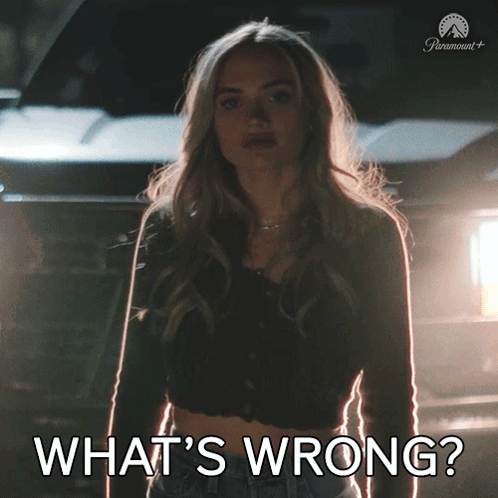 a woman is standing in front of a car with the words what 's wrong written below her