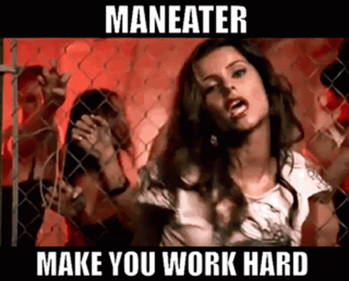 A Woman Is Standing In Front Of A Chain Link Fence With The Words Maneater Make You Work Hard Below Her GIF