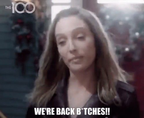 A Woman Is Standing In Front Of A Christmas Tree And Saying `` We 'Re Back Bitches ! '' GIF